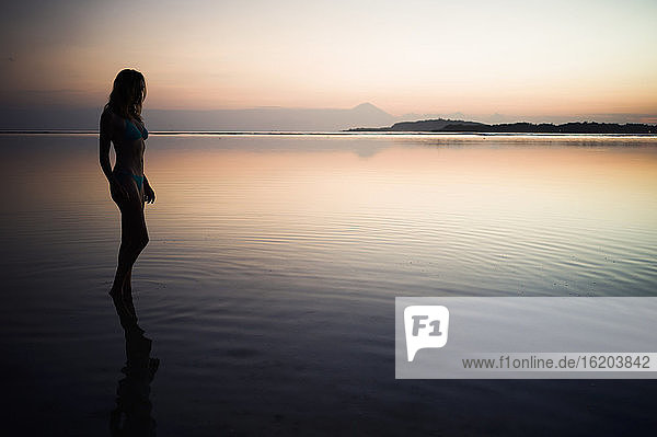 Frau bei Sonnenuntergang im Meer stehend  Gili Air  Indonesien
