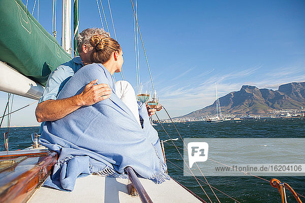 Couple on yacht with wine  woman wrapped in blanket