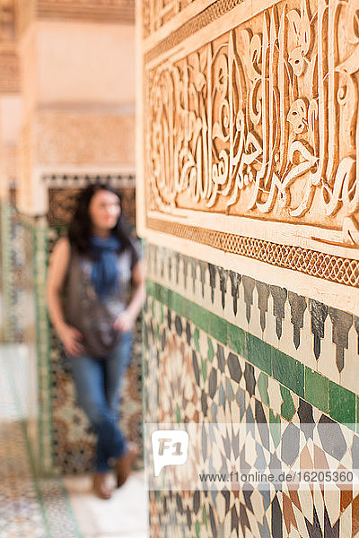 Mittlere erwachsene Frau  an eine geflieste Wand gelehnt  Fokus auf den Vordergrund  Marrakesch  Marokko