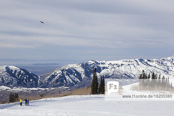 Drei Personen lassen in einer Winterlandschaft einen Drachen steigen  Eden  Utah  USA