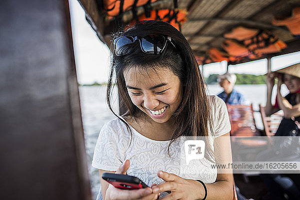 Woman looking at photo in mobile phone on cruise boat  Mekong Delta  Vietnam