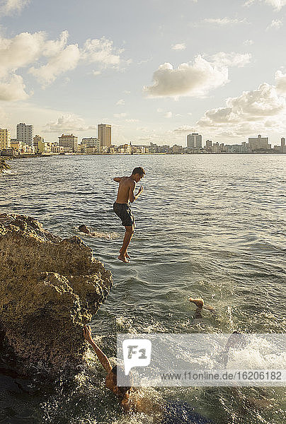 Boys jumping from rocks into sea, Havana, Cuba
