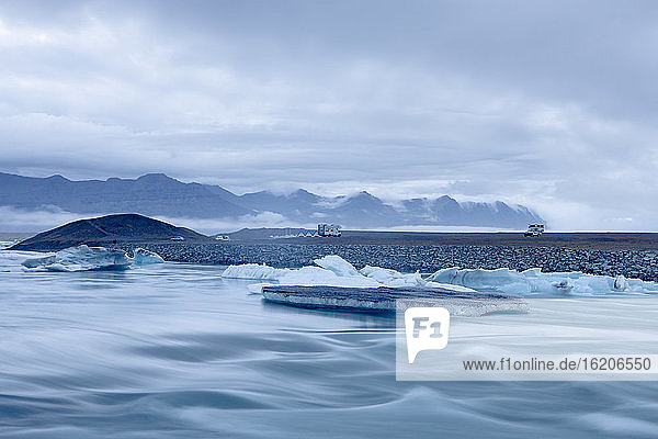 Bergkette und Eisberge  die auf einer Gletscherflusslagune schwimmen  Jokulsarlon  Island