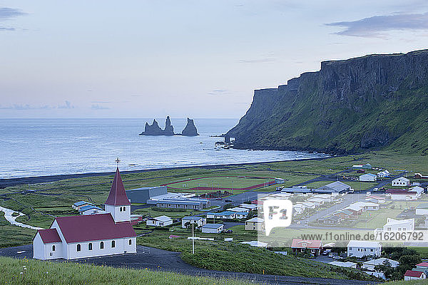 High angle view of Reynisdrangar basalt sea stacks and the village of Vik, Myrdalshreppur, Iceland