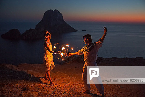 Pärchen tanzt mit Feuer Sonnenuntergang  Ibiza  Es Vedra Felsen im Hintergrund