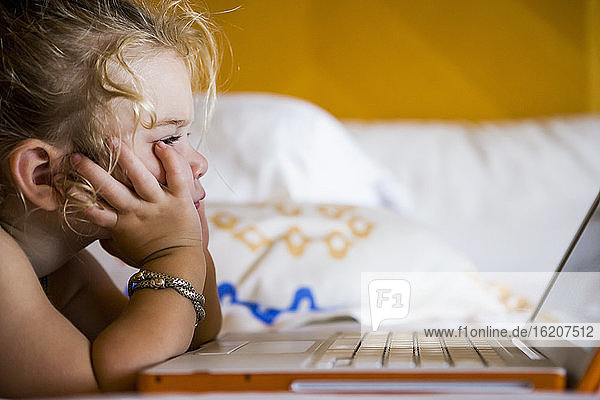 3 year old girl looking at laptop in hotel room