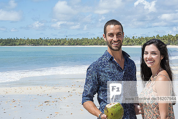Ein gutaussehendes hispanisches (lateinisches) Paar lächelt und steht zusammen an einem einsamen Strand  Brasilien  Südamerika
