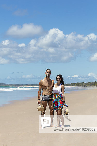 A good-looking Hispanic (Latin) couple on a deserted beach smiling to camera  Brazil  South America