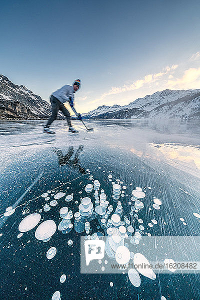 Mann spielt Eishockey auf dem zugefrorenen Silsersee  Engadin  Kanton Graubünden  Schweiz  Europa