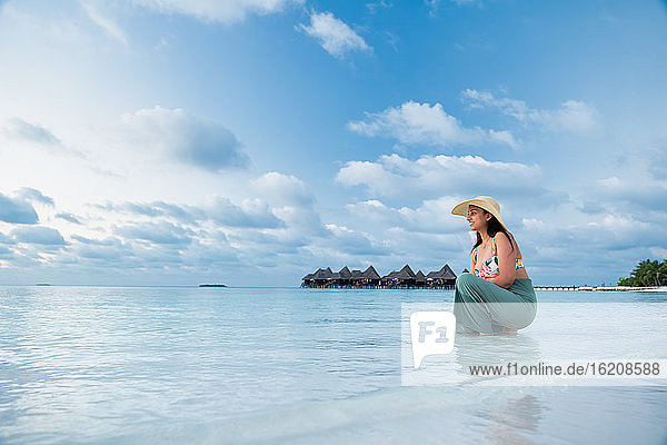 Eine indische Touristin am blauen Wasser und weißen Sandstrand  Die Malediven  Indischer Ozean  Asien