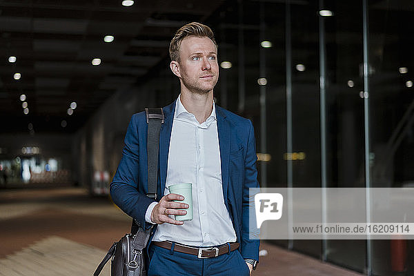 Businessman drinking coffee while walking in city