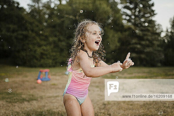 Glückliches Mädchen spielt mit Seifenblasen im Garten