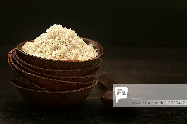 Bowl of sea salt on wooden table, close up