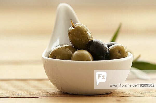 Löffel mit Oliven auf Holztisch  Nahaufnahme