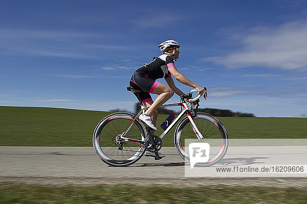 Deutschland  Bayern  Mittlere erwachsene Frau fährt Rennrad