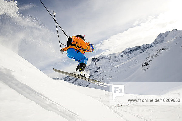 Österreich,  Mann springt mit Ski auf Berg