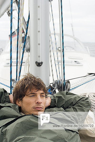 Germany  Baltic Sea  Lübecker Bucht  Young man lying on deck of yacht  portrait