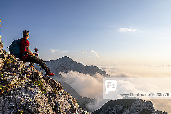 Wanderer bewundert die Aussicht  während er auf dem Gipfel eines Berges in den Bergamasker Alpen  Italien  sitzt