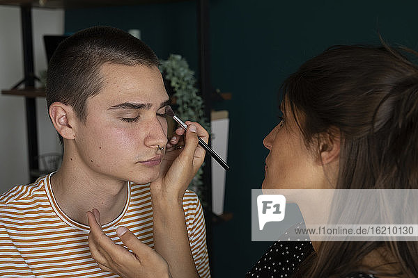 Junge Frau trägt Make-up auf einen Mann auf