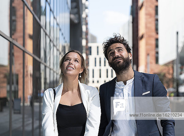 Geschäftsmann und Geschäftsfrau im Geschäftsviertel der Stadt mit Blick nach oben