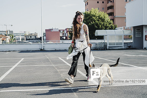 Frau geht mit Hund auf einem Parkplatz spazieren