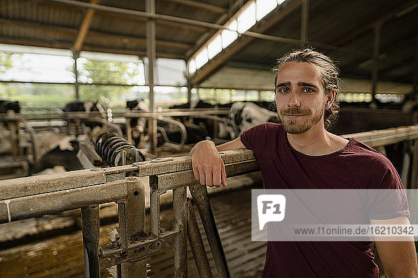Porträt eines jungen Bauern im Kuhstall auf einem Bauernhof