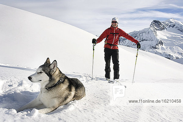 Österreich  Mann beim Skifahren mit Lawinenhund im Schnee