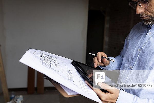 Architekt bei der Arbeit mit Tablet und Bauplan