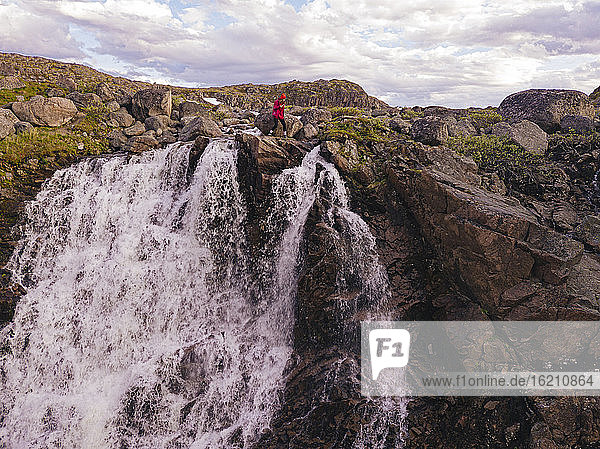 Russland  Gebiet Murmansk  Teriberka  Luftaufnahme einer Wanderin am Rande eines plätschernden Wasserfalls