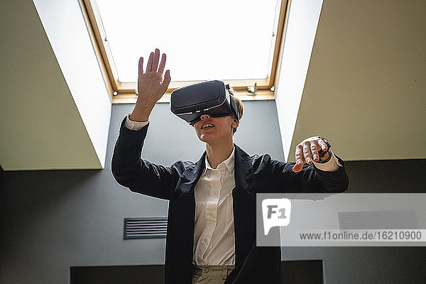 Geschäftsfrau gestikuliert  während sie ein Virtual-Reality-Simulator-Headset im Büro trägt