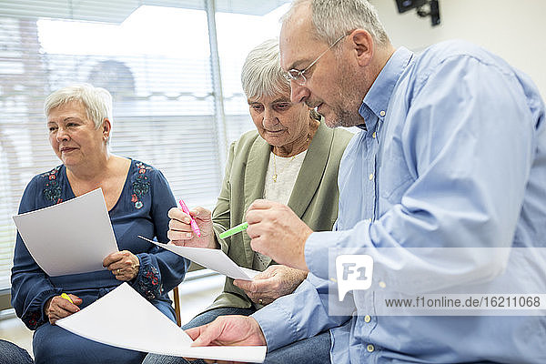 Senioren in einer Therapiegruppe in einem Seniorenheim  die Notizen auf Zetteln notieren