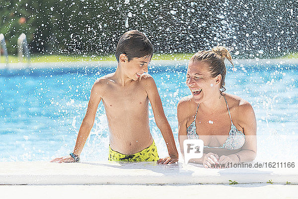 Hemdloser Junge schaut Mutter lachend im Schwimmbad an