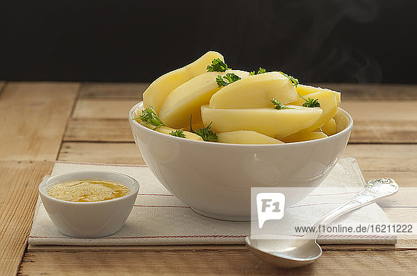 Schüssel mit Kartoffeln  Butter und Löffel auf Holztisch  Nahaufnahme