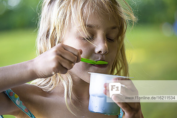Blondes Mädchen isst Eiscreme in einem Einwegbecher