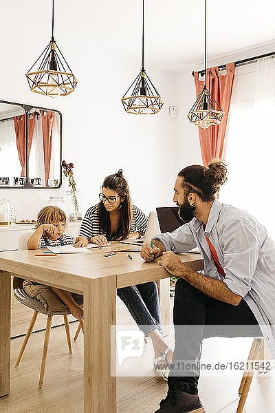 Eltern betrachten niedliche Tochter Malerei auf Esstisch zu Hause