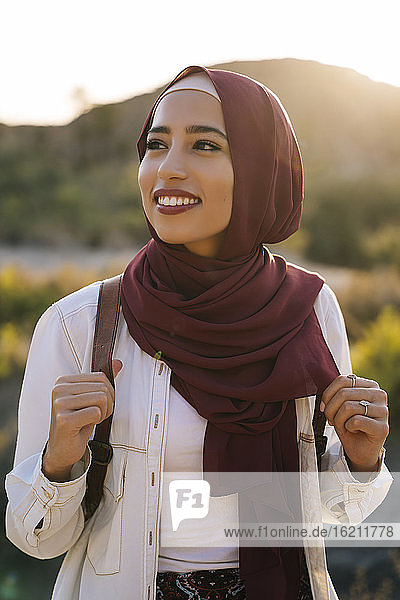 Lächelnde junge Touristin mit Hijab in Wüstenlandschaft  die sich umschaut