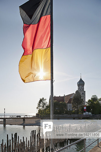 Deutschland  Wasserburg  Blick auf deutsche Flagge am Hafen und Kirche im Hintergrund