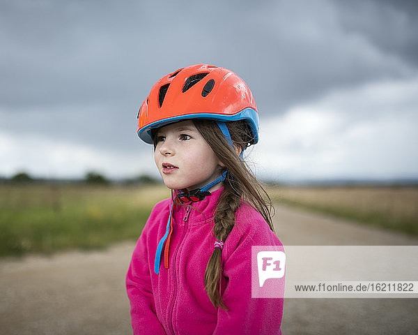 Girl wearing orange cycling helmet looking sideways