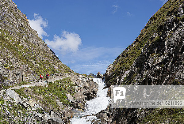 Italy  View of Pfunderer Berge with hikers walking near stream