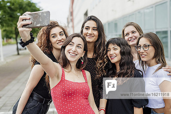 Weibliche Freunde nehmen Selfie mit Smartphone  während in der Stadt stehen