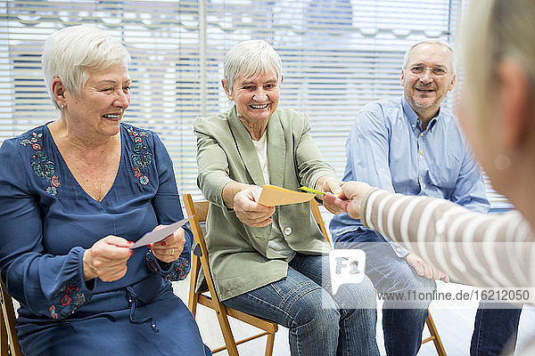 Seniors in retirement home attending group therapy using colorful paper cards