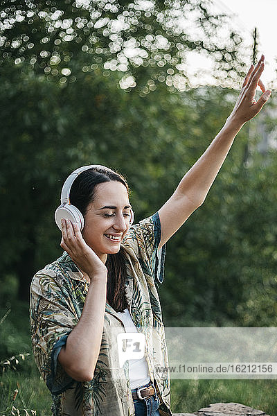Happy woman dancing while enjoying music in public park