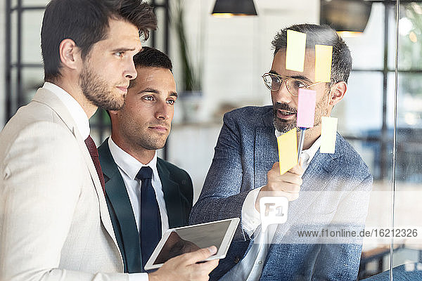 Businessman explaining coworkers over sticky notes during meeting