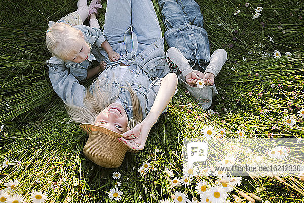 Lächelnde Mutter mit Tochter und Sohn auf einer Blumenwiese liegend
