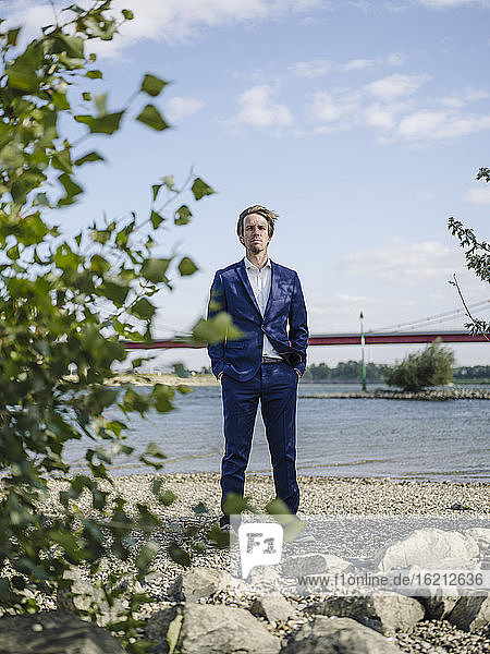 Serious Businessman standing against Rhine river and sky