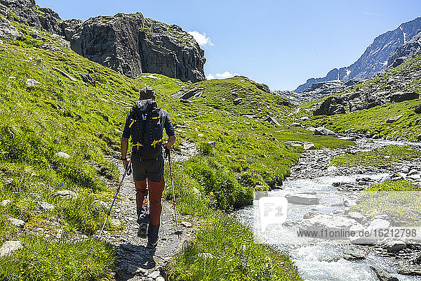 Mann beim Wandern am Bach auf einem Berg in den westlichen Rätischen Alpen  Sondrio  Italien