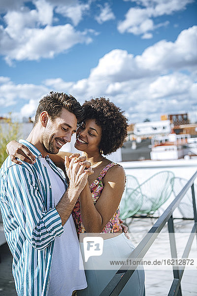 Happy multi-ethnic couple dancing on penthouse patio