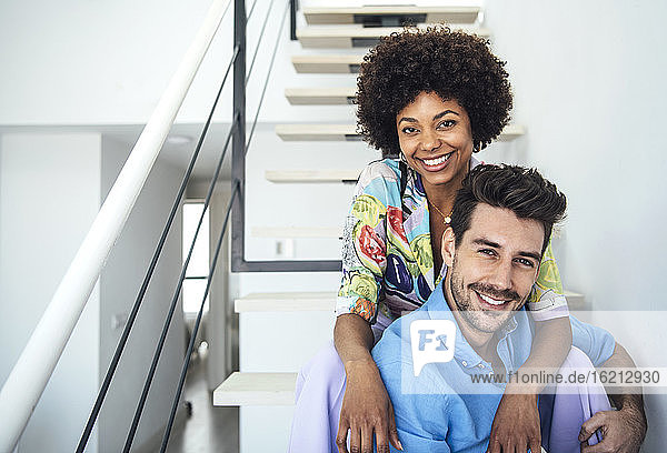 Happy couple sitting on floating stairs in penthouse
