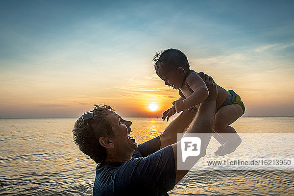 Vietnam  Phu Quoc Insel  Ong Lang Strand  Vater hält Baby am Strand bei Sonnenuntergang