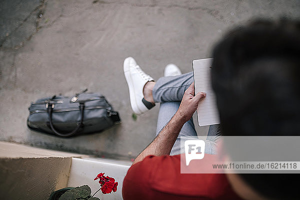 Geschäftsmann liest ein Buch  während er auf der Fensterbank im Freien sitzt
